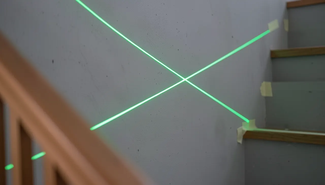 Schéma laser vert projeté sur mur d'escalier indiquant l'axe d'accrochage à 1,60 m